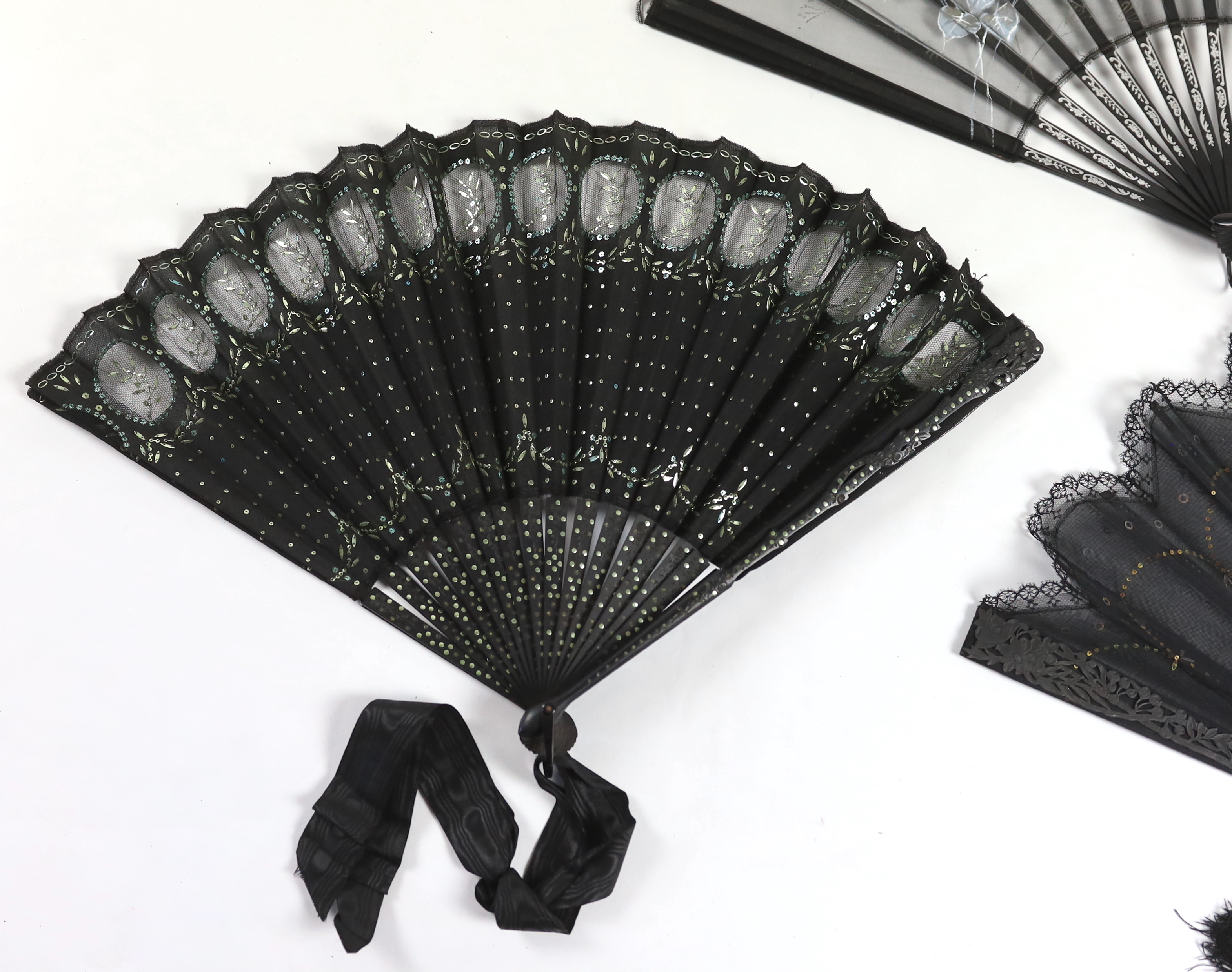 An Edwardian black silk and ornate sequin fan, a similar fan with carved ebony guards and a fine gauze fan with painted sprig and butterfly decoration (3)